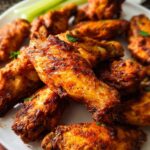 A close-up of a plate piled high with delicious, crispy 25-ingredient chicken wings, garnished with parsley.