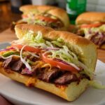 Close-up of a steak sandwich with melted cheese, lettuce, tomato, and onion, part of 7-Ingredient Sandwich Ideas Recipes.
