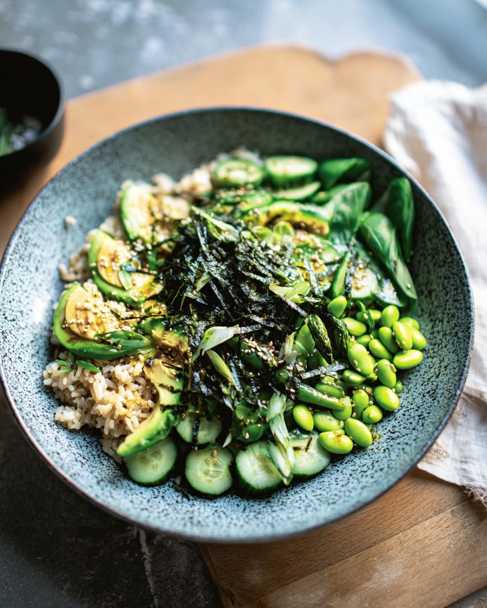 A vibrant and healthy rice bowl featuring brown rice, sliced avocado, edamame, cucumber, and seaweed. A perfect beginner rice bowl recipe.