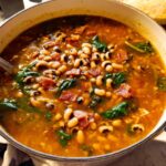 A close-up of a steaming pot of black eyed pea soup with spinach and bacon, part of The Ultimate Soup Recipes Guide for Beginners.