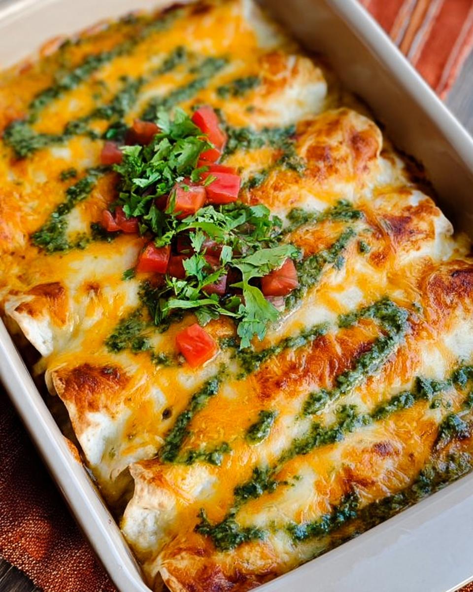 Close-up of baked chicken enchiladas topped with melted cheese, green sauce, and diced tomatoes.