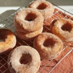 A close-up of freshly made cinnamon sugar donuts cooling on a wire rack, perfect for breakfast ideas.