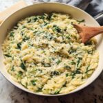 Close-up of creamy orzo pasta with spinach and grated Parmesan cheese, a perfect addition to your Veggie Sides Recipes.