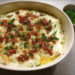 A close-up of creamy mashed potatoes topped with crispy bacon bits and fresh parsley, a delicious recipe idea.