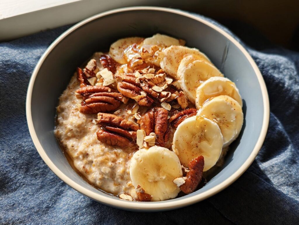 A bowl of oatmeal topped with sliced bananas, pecans, and a drizzle of honey, perfect for busy weeknight breakfasts.