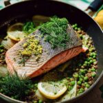 A beautiful one-pan meal featuring a salmon fillet atop lentils, peas, fennel, and lemon slices, perfect for healthy meals recipes.