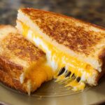 Close-up of a restaurant-style grilled cheese sandwich with melted cheese oozing out.