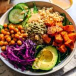 A vibrant and healthy rice bowl recipe featuring quinoa, roasted sweet potatoes, chickpeas, avocado, and red cabbage.