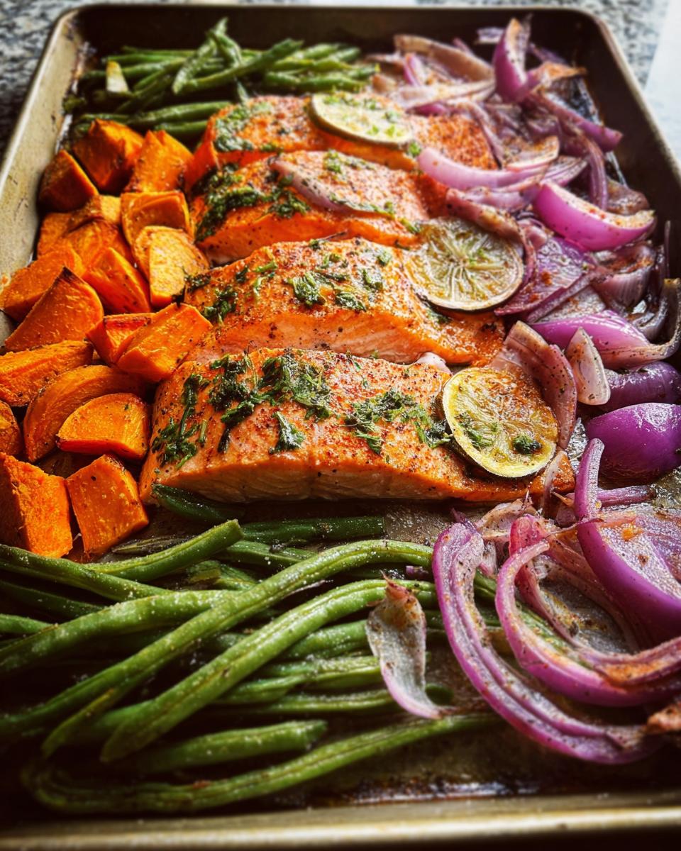 Sheet pan with salmon fillets, roasted sweet potatoes, green beans, and red onions, perfect for salmon recipes meal prep.
