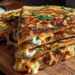 Close-up of Cheesy Hot Honey Chicken Quesadillas, sliced and stacked, with gooey melted cheese oozing out, garnished with parsley.