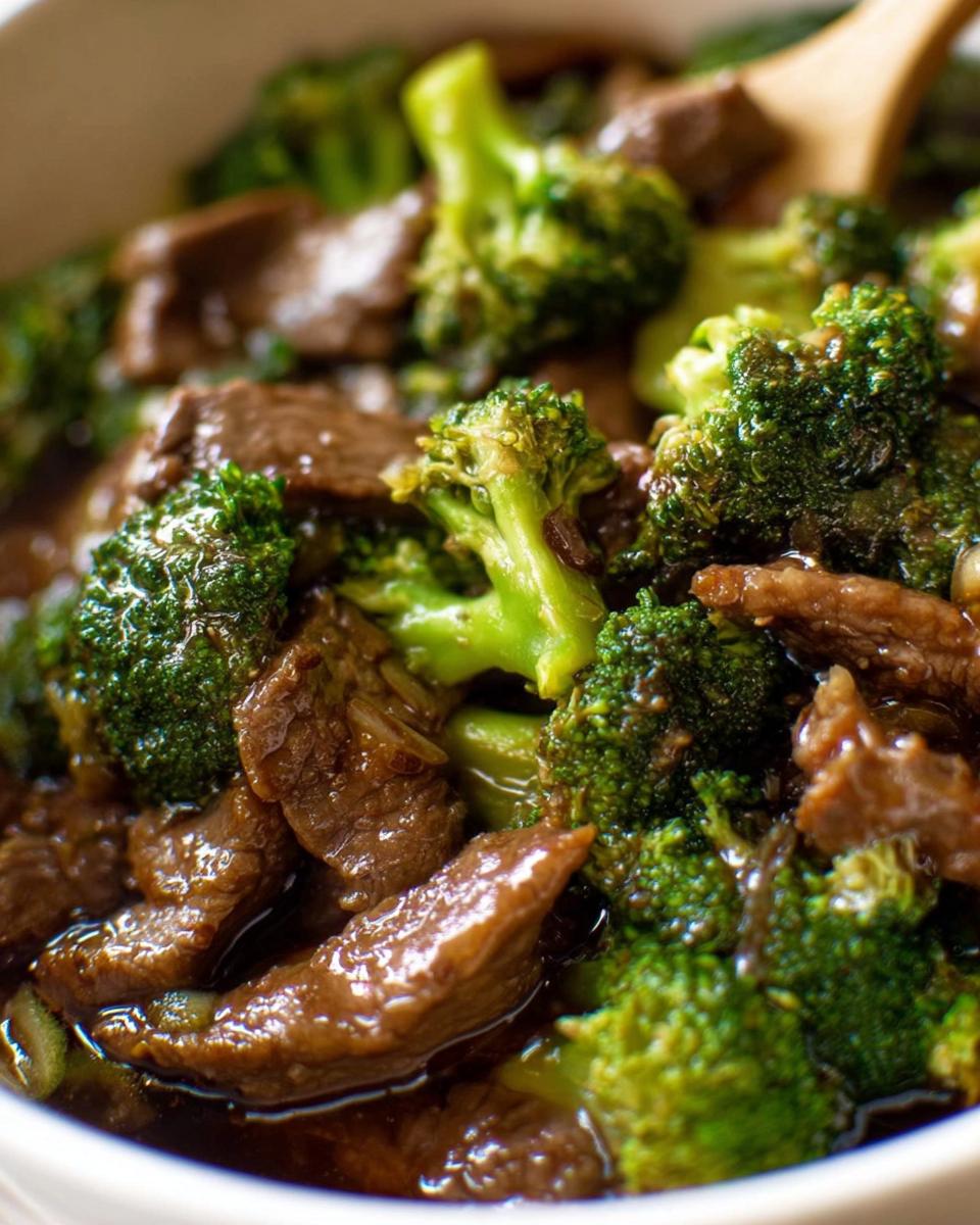Close-up of tender beef strips and vibrant broccoli florets in a glossy sauce, a classic Chinese Beef and Broccoli dish.