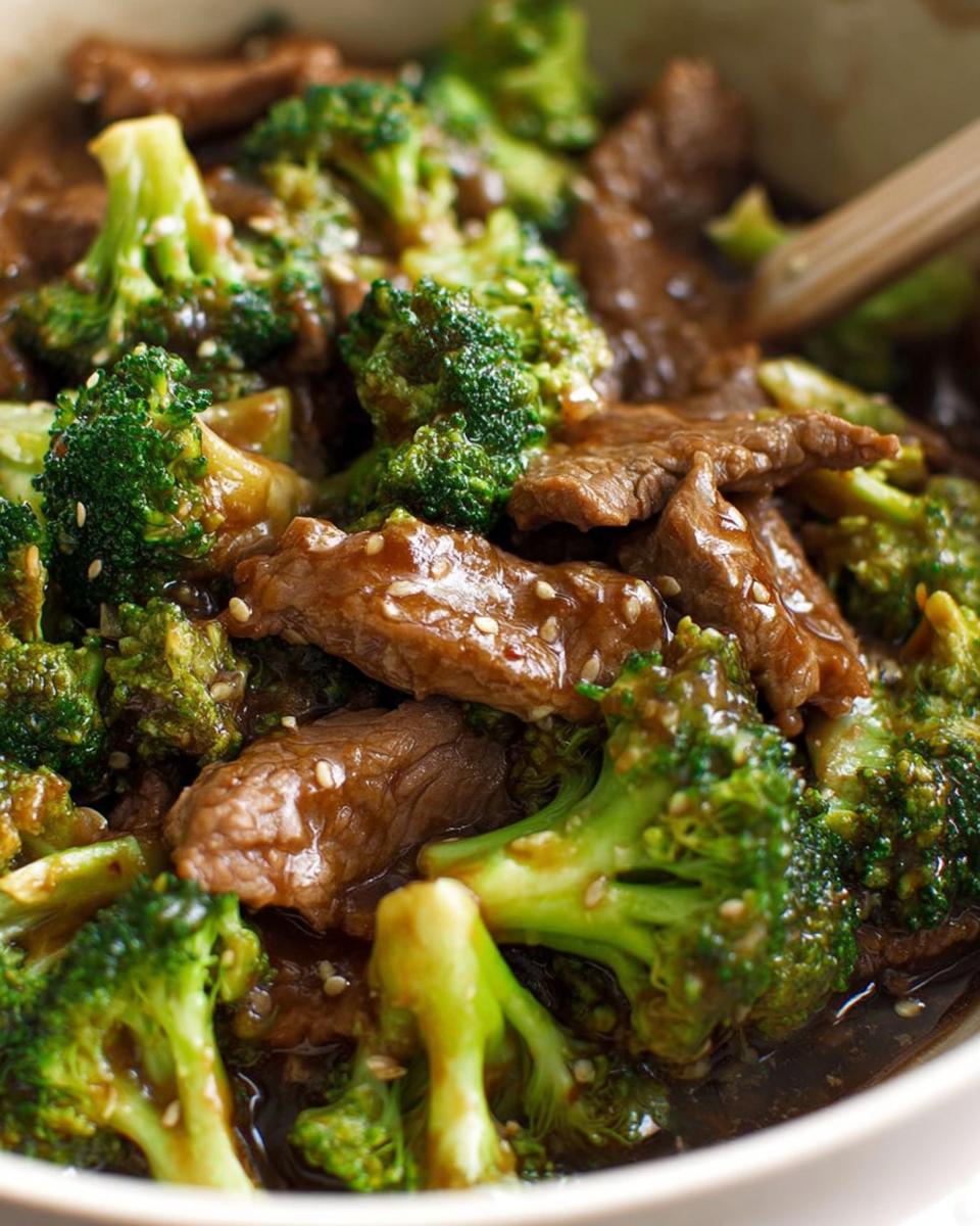 Close-up of Chinese Beef and Broccoli stir-fry with tender beef slices and vibrant green broccoli florets in a savory sauce, sprinkled with sesame seeds.