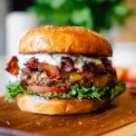 A juicy and delicious Crack Burger with bacon, cheese, lettuce, and tomato on a toasted bun.