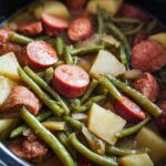 Close-up of Crockpot Kielbasa and Green Beans with potatoes in a slow cooker.