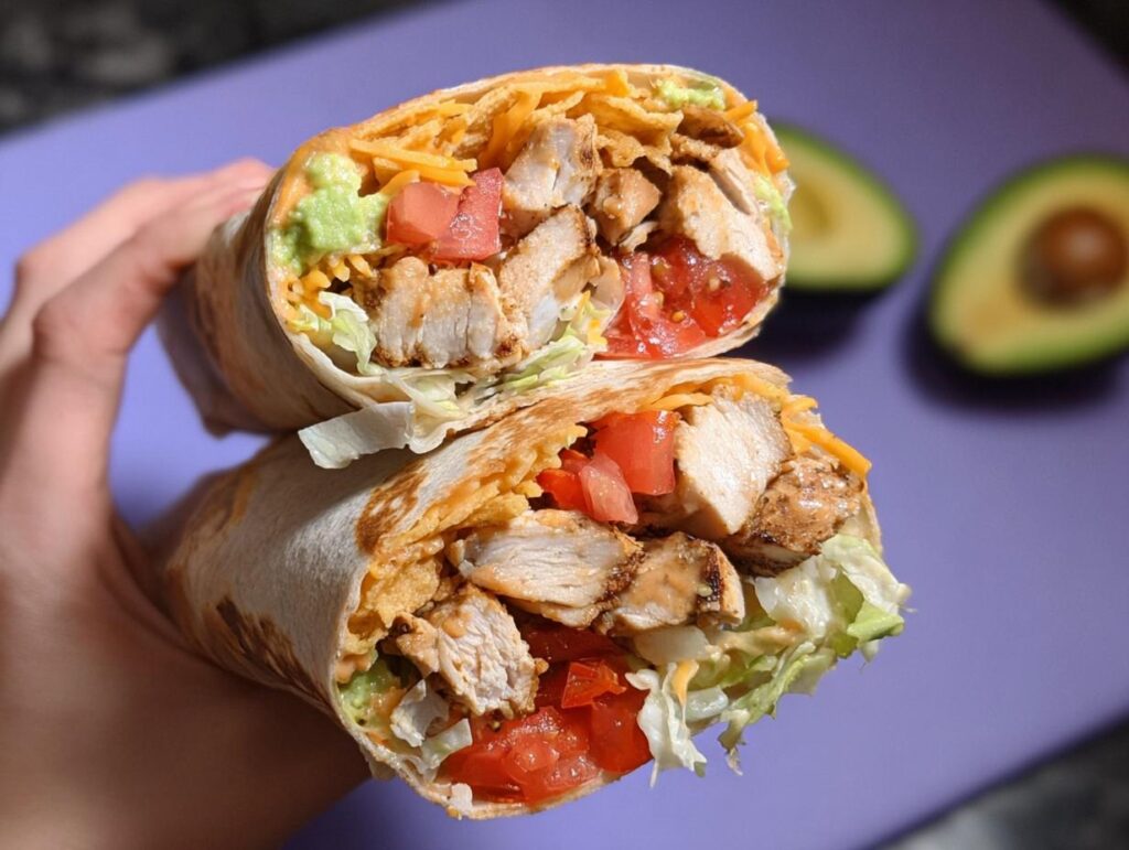 A halved Easy Chipotle Ranch Grilled Chicken Burrito filled with grilled chicken, lettuce, tomato, cheese, and avocado.