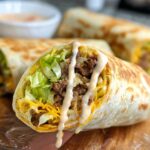 Close-up of a Homemade Big Mac Wrap cut in half, showing seasoned ground beef, shredded lettuce, cheese, and special sauce.