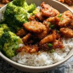A delicious Honey Garlic Pork Rice Bowl featuring tender pork pieces, fluffy white rice, and steamed broccoli florets, garnished with green onions.