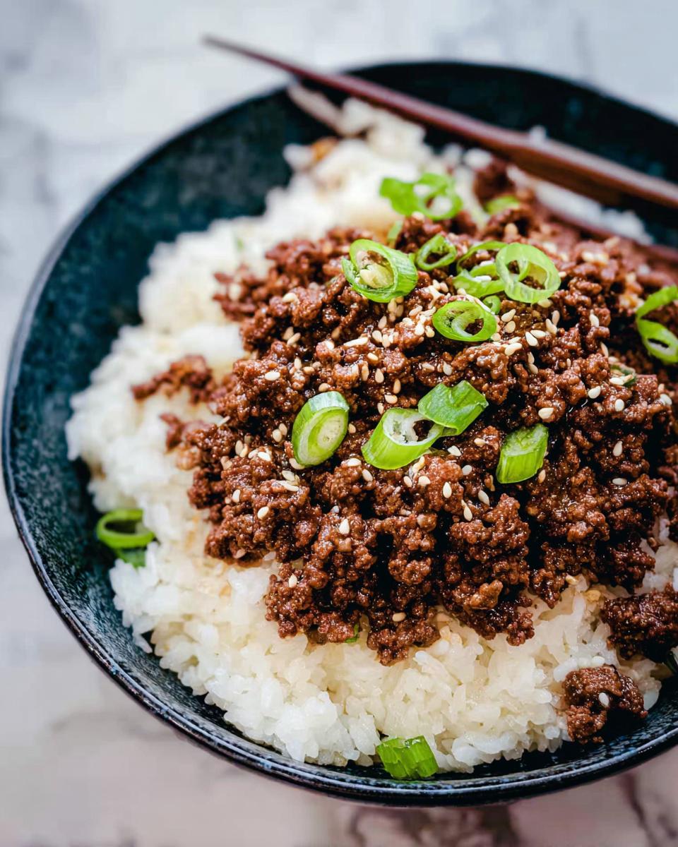 A close-up of a Korean Ground Beef Bowl, featuring seasoned ground beef over fluffy white rice, garnished with sesame seeds and green onions.