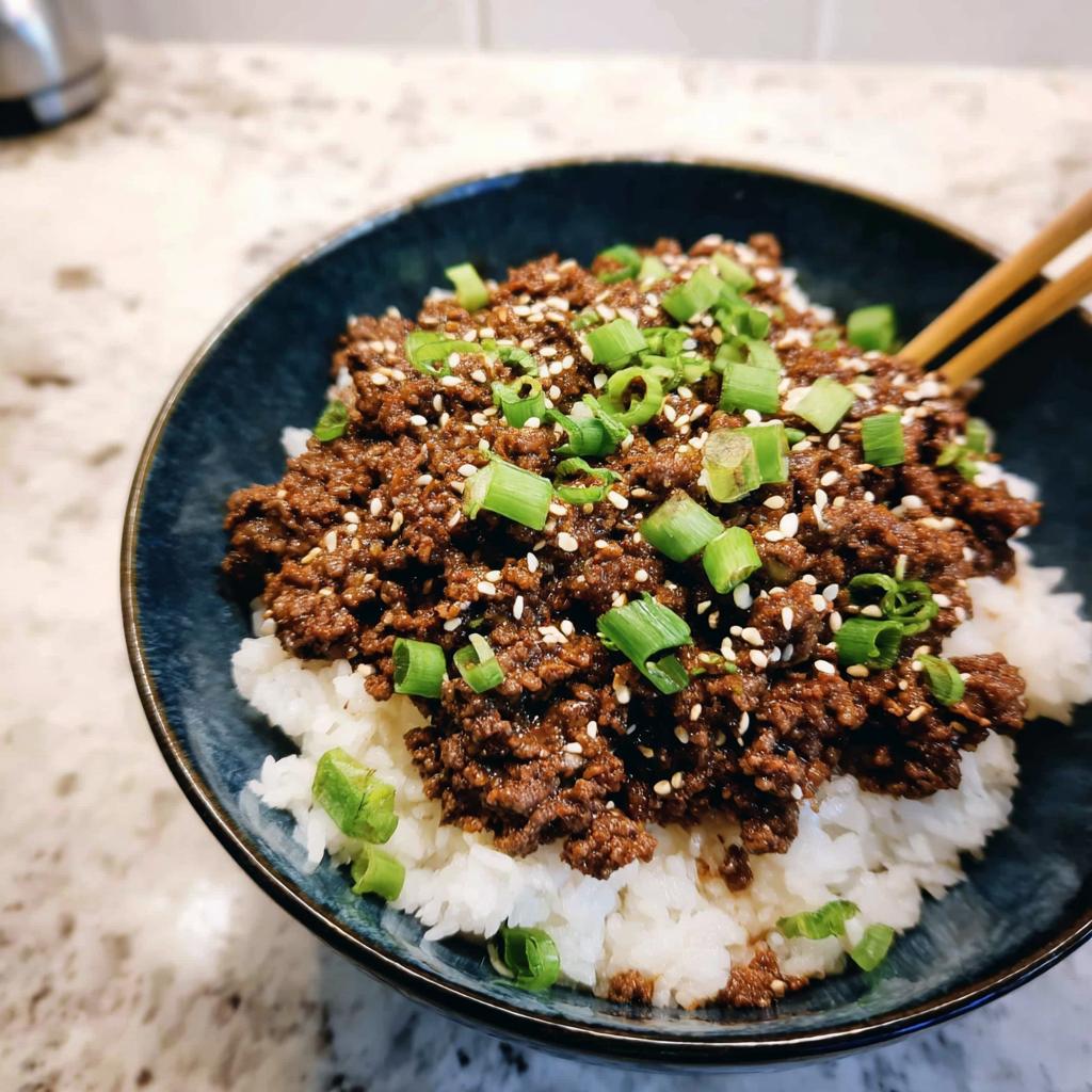 A close-up of a Korean Ground Beef Bowl, featuring seasoned ground beef over white rice, topped with sesame seeds and chopped green onions.