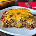 A delicious slice of Low-Carb Bacon Cheeseburger Casserole topped with melted cheese and pickles.
