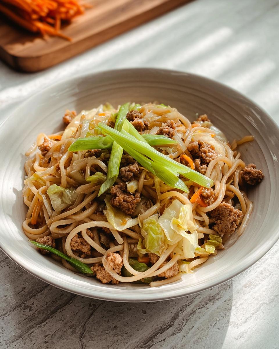 A close-up of a Potsticker Noodle Bowl with Pork & Cabbage Slaw, garnished with green onions.