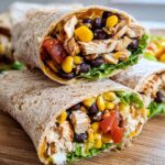 Two halves of a Southwest Chicken Wrap filled with grilled chicken, black beans, corn, tomatoes, and lettuce.