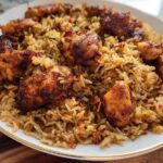 A close-up of a white plate filled with flavorful BBQ Chicken and Rice, featuring tender chicken pieces mixed with seasoned rice.