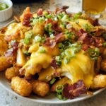A hearty plate of Breakfast Poutine with Hollandaise Sauce, crispy tater tots, bacon, and green onions.