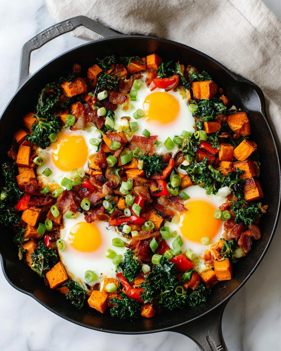 A cast iron skillet filled with a hearty BREAKFAST SWEET POTATO hash, topped with four sunny-side-up eggs, crispy bacon, and green onions.