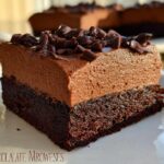 A rich slice of Chocolate Mousse Brownies, featuring a dense brownie base topped with smooth chocolate mousse and chocolate shavings.