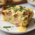 A delicious slice of Easy Eggs Benedict Casserole topped with hollandaise sauce and chives.