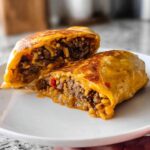 A split Easy Grilled Cheese Burrito Copycat Recipe showing seasoned ground beef, rice, and melted cheese inside a golden-brown tortilla.