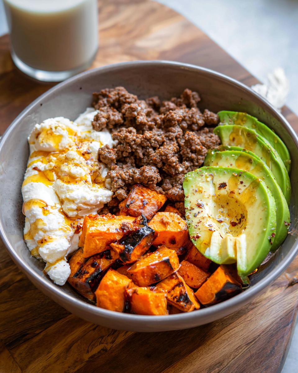 A delicious Ground Beef Hot Honey Bowl featuring seasoned ground beef, grilled sweet potatoes, creamy cottage cheese with honey, and sliced avocado.