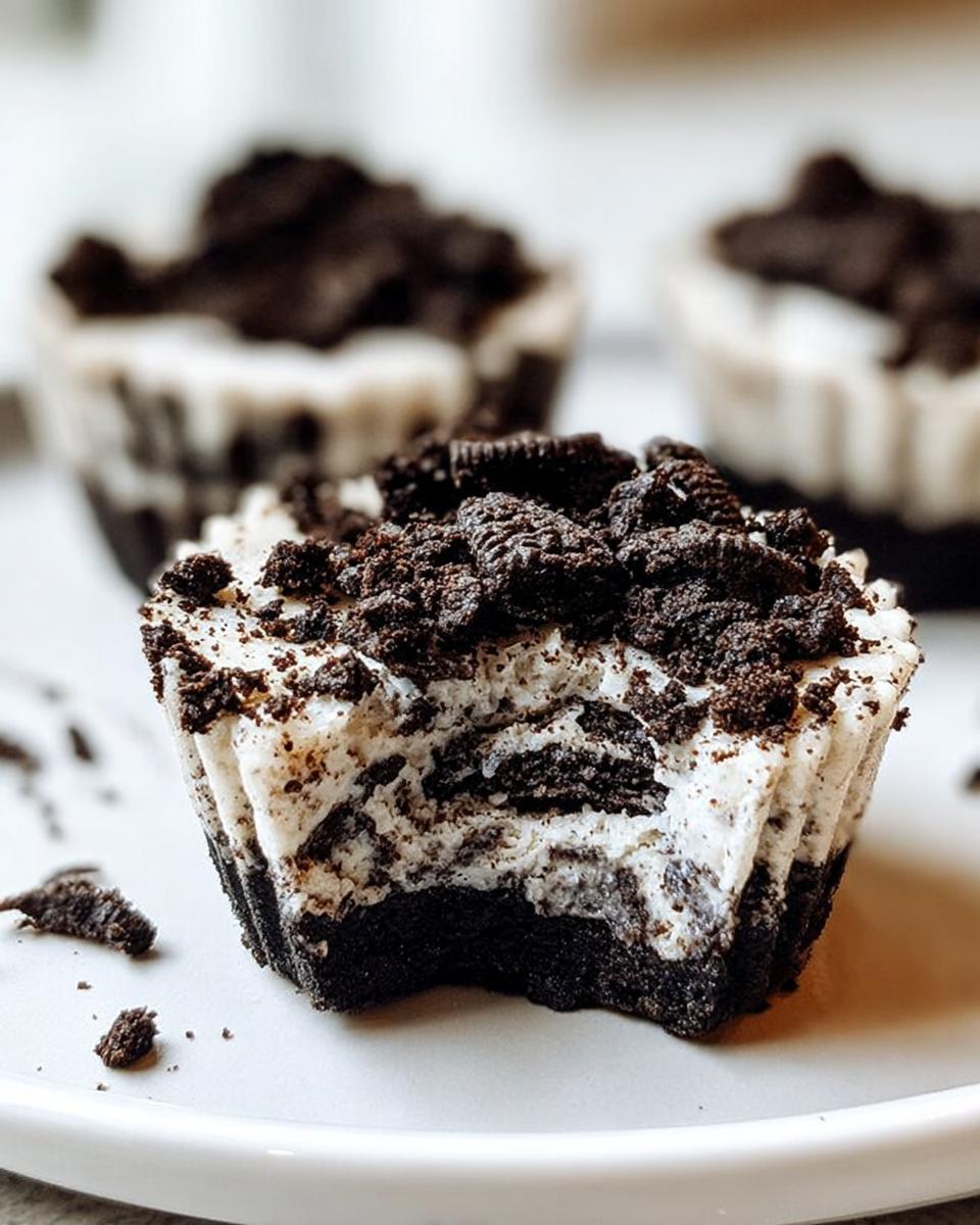 A close-up of a Healthy No-Bake Oreo Cheesecake Bite with a bite taken out, showing the creamy filling and Oreo cookie crust.