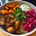 A vibrant Hot Honey Chicken Bowl featuring glazed chicken, roasted sweet potatoes, pickled red cabbage, cilantro, and a dollop of lime crema.