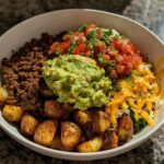 A delicious Loaded Potato Taco Bowl filled with seasoned ground beef, roasted potatoes, guacamole, pico de gallo, and shredded cheese.