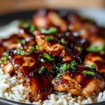 A close-up of delicious One-Pan Honey BBQ Chicken Rice, featuring glazed chicken pieces over fluffy white rice, garnished with green onions.