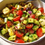 A bowl of Simple Zesty Mediterranean Avocado Egg Salad with avocado, tomatoes, olives, and cheese.
