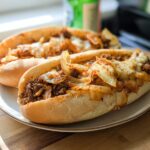 Two delicious Spicy Kimchi Bulgogi Cheesesteak sandwiches filled with seasoned beef, kimchi, onions, and melted cheese.