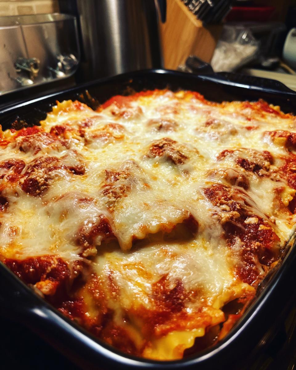 A close-up of a bubbly, cheesy ravioli bake in a black baking dish, ready for an easy dinner.