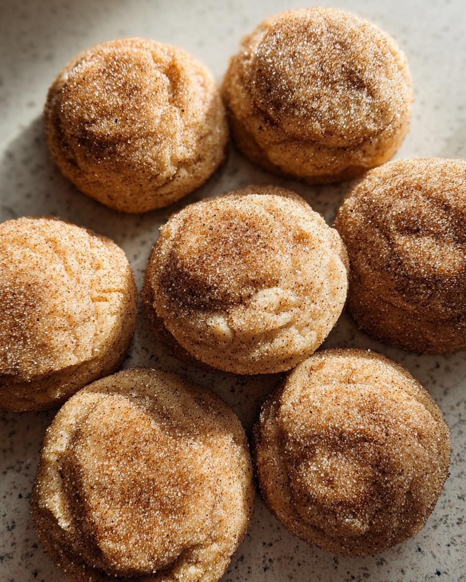 A close-up of several chewy churro cookies, generously coated in cinnamon sugar.