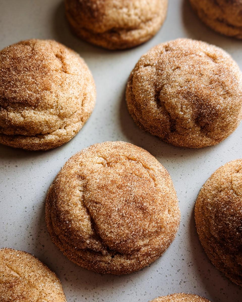 A close-up overhead view of several chewy churro cookies, generously coated in cinnamon sugar.