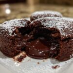Close-up of a chocolate lava cake, oozing with molten chocolate, dusted with powdered sugar.