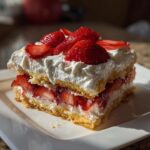 A slice of creamy strawberry icebox cake with layers of sponge cake, whipped cream, and fresh strawberries.