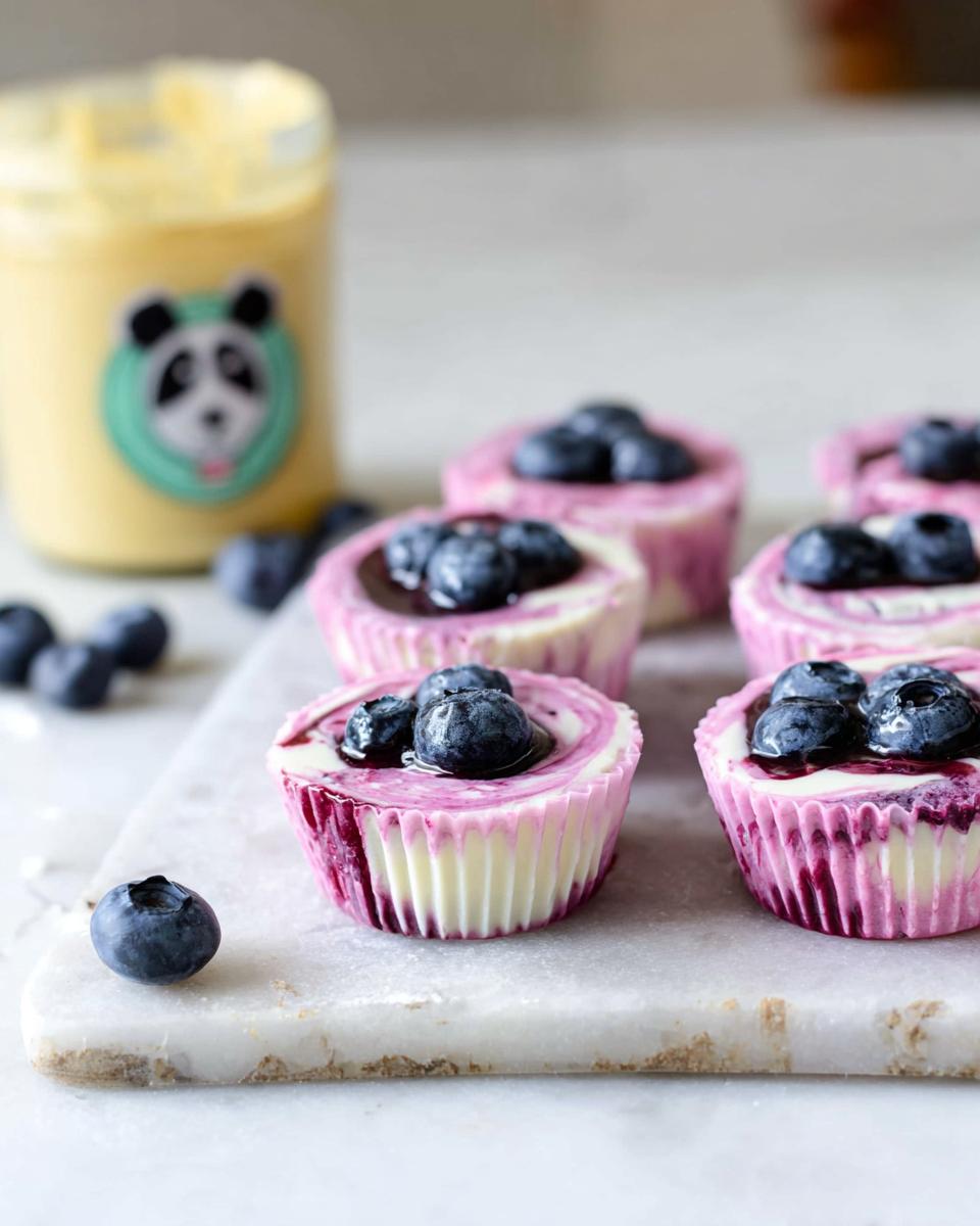 Close-up of Easy Blueberry Swirl Yogurt Bites topped with fresh blueberries and a swirl of blueberry sauce.
