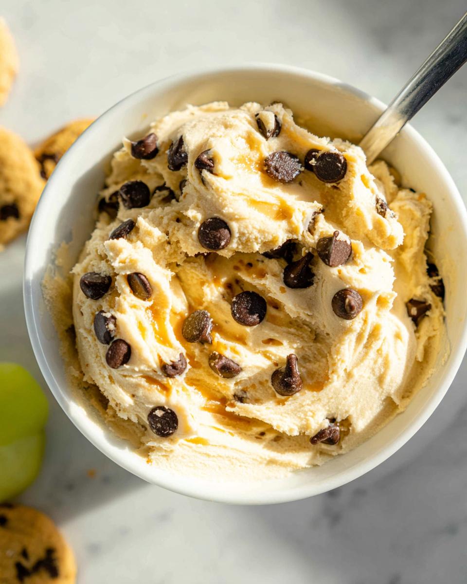 A bowl of creamy Greek Yogurt Cookie Dough with chocolate chips and a drizzle of caramel.