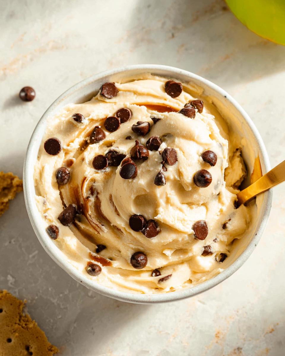 A bowl of creamy Greek yogurt cookie dough recipe topped with chocolate chips and a drizzle of caramel.