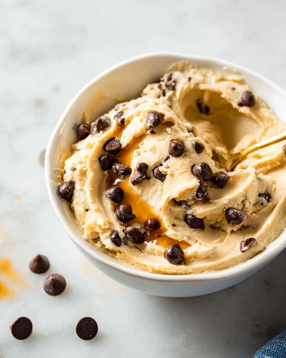 A bowl of creamy Greek yogurt cookie dough recipe, loaded with chocolate chips and drizzled with caramel.