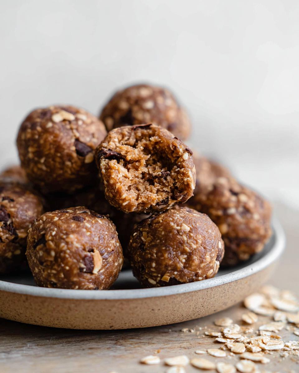 A close-up of No-Bake Chocolate Peanut Butter Protein Balls, with one ball broken in half to show the texture.