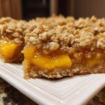 Close-up of delicious peach crumble bars with a buttery oat topping and a gooey peach filling.